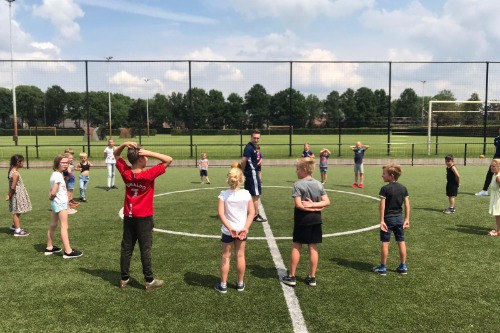 Kinderen in cirkel luisterend naar uitleg